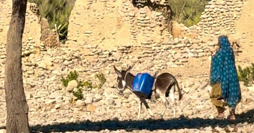 Women and children carrying water containers across rocky mountain paths in Kunraj, Balochistan due to clean water shortage
