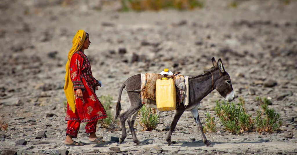 Women and children carrying water containers across rocky mountain paths in Kunraj, Balochistan due to clean water shortage