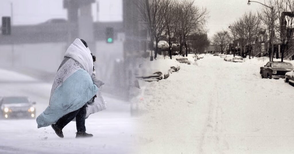 A person walks through blowing snow wrapped in blankets while nearby streets and vehicles are buried under deep snowfall.