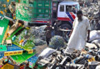 Workers sorting electronic scrap and wires in an open scrapyard surrounded by piles of discarded equipment and debris.