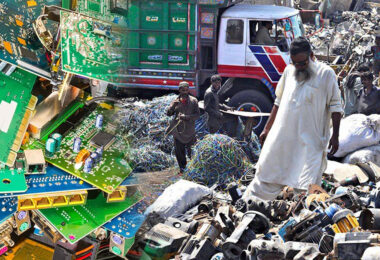 Workers sorting electronic scrap and wires in an open scrapyard surrounded by piles of discarded equipment and debris.