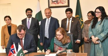 Officials from Pakistan and Norway sign a bilateral climate agreement under Article 6.2 of the Paris Agreement during a formal ceremony in Islamabad, with representatives standing behind and national flags displayed.